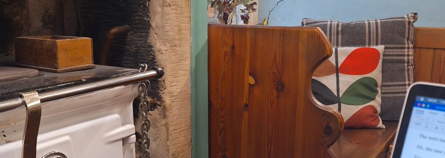 a laptop on a table, a cup of tea, a stove, a cosy scene